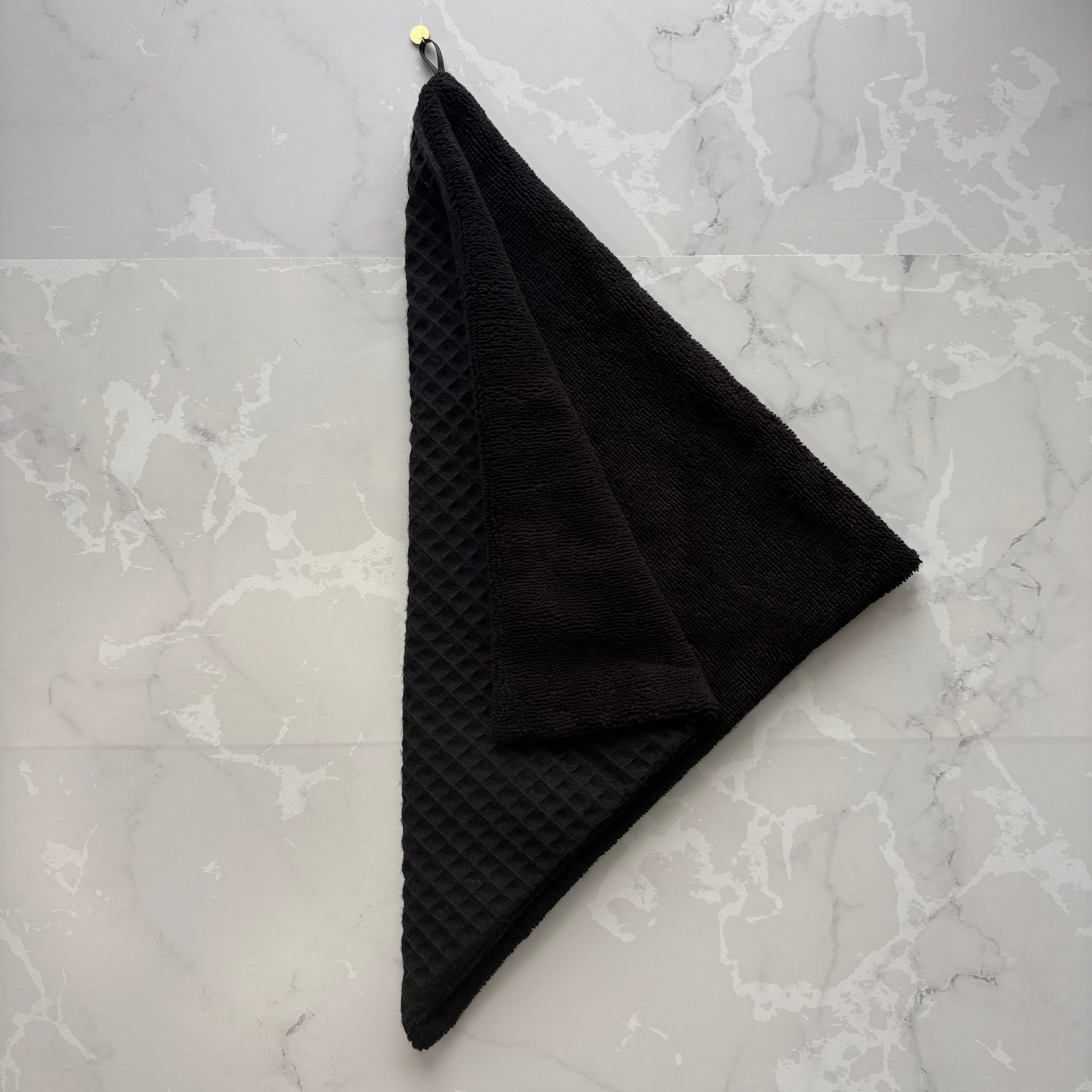 serviette visage en éponge bambou et nid d'abeille noir avec un logo médaillon.