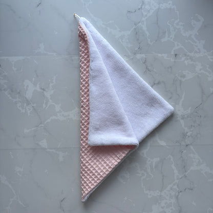 serviette visage en éponge bambou blanc et nid d'abeille rose pale avec un logo médaillon.